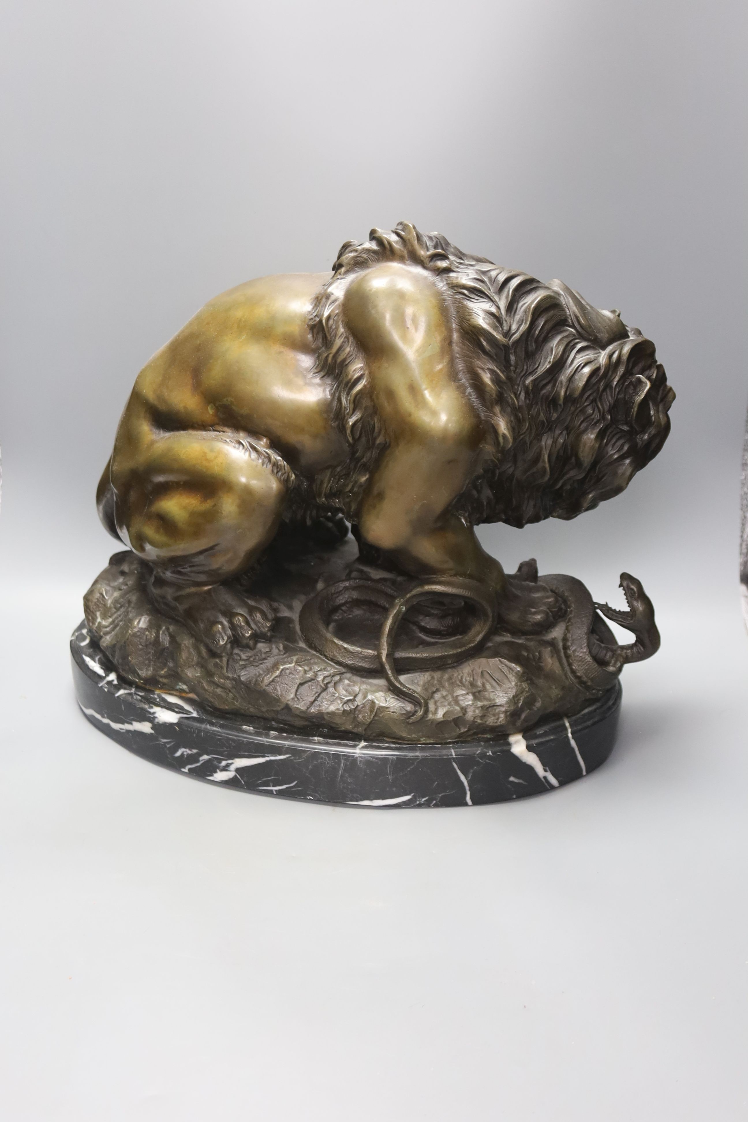 After Antoine-Louis Barye. A reproduction bronze of a tiger attacking a serpent, on a marble plinth, overall height 35cm